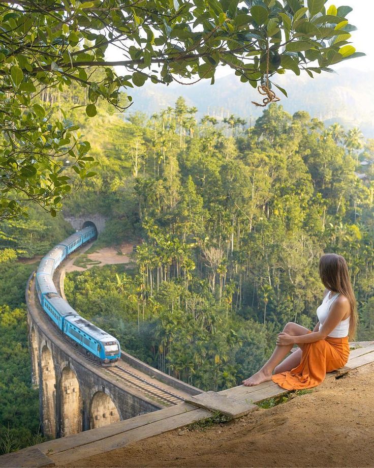 Blue train crossing Nine Arch Bridge in Ella Sri Lanka with tourist watching from viewpoint